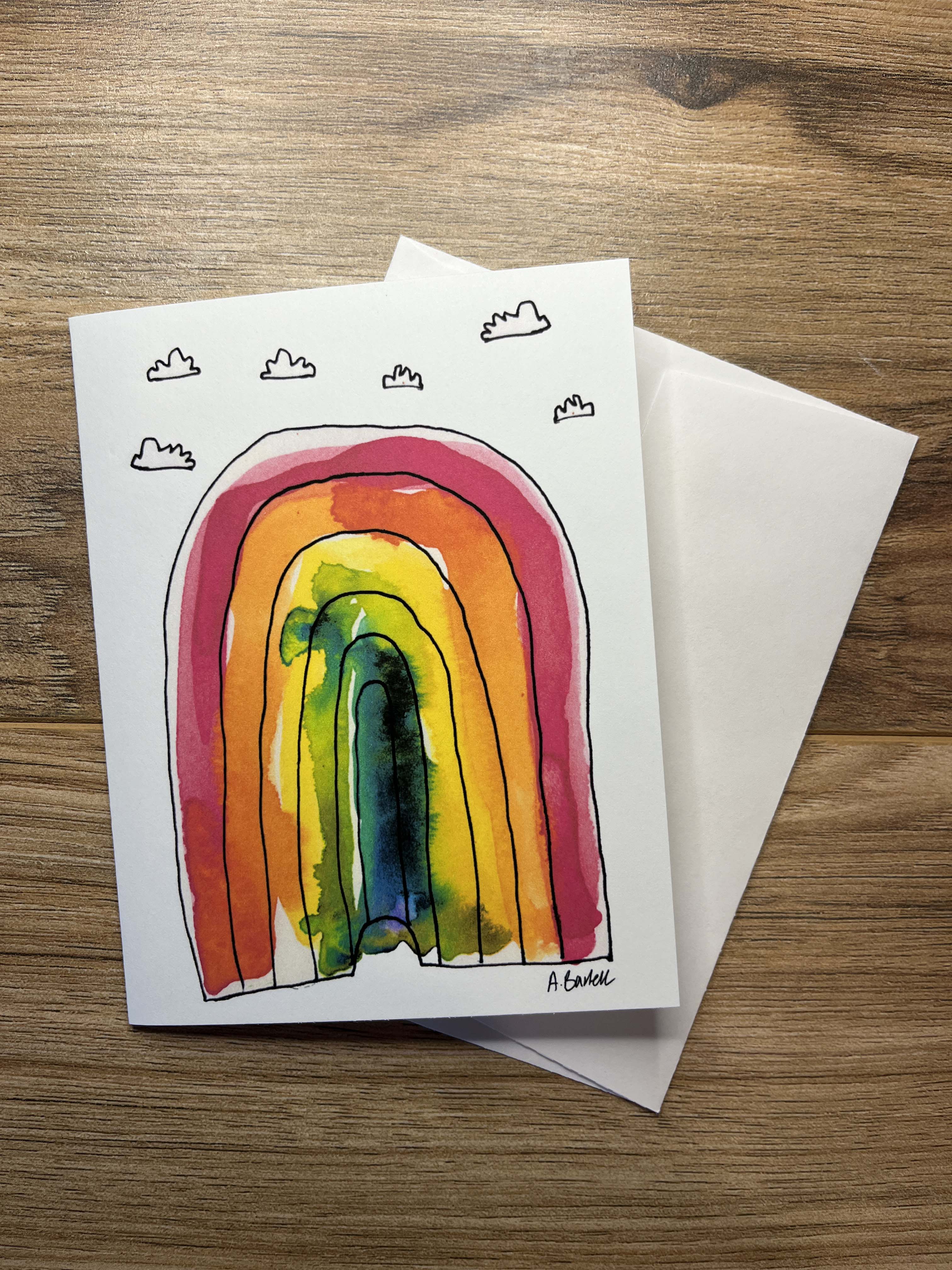 Greeting card with a colorful rainbow illustration and envelope on a wooden surface